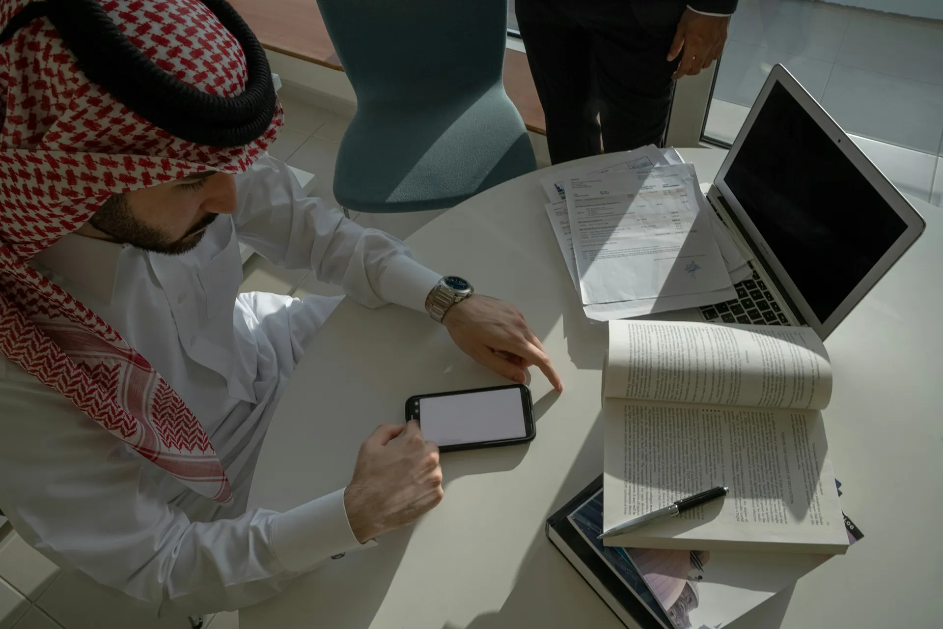 طالب سعودي يذاكر على مكتبه باستخدام حاسوب محمول وكتاب وملاحظات استعدادًا للاختبار