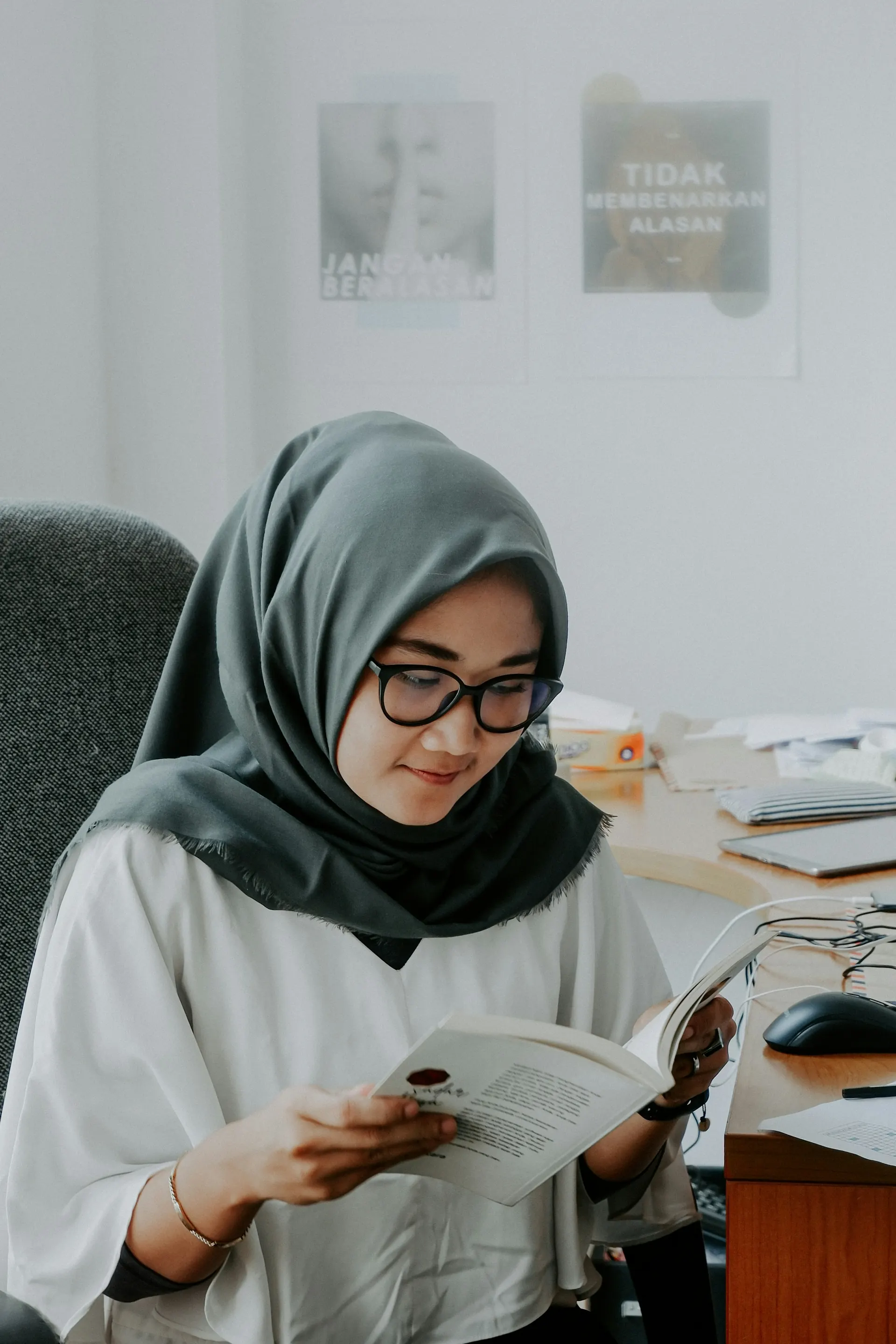 طالبة بالحجاب تقرأ كتابًا على مكتب الدراسة