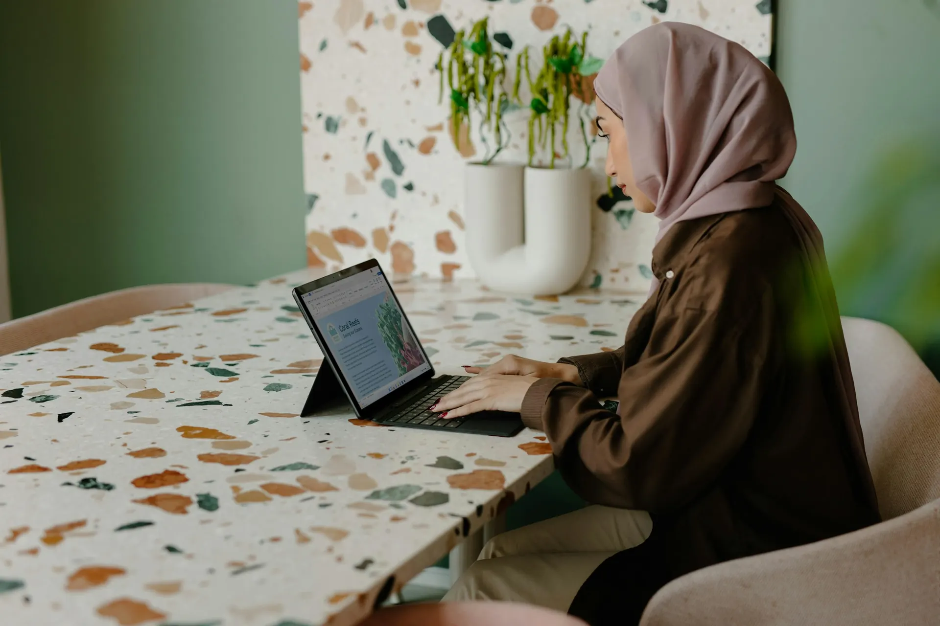 طالبة تتدرب على اللغة الإنجليزية عبر حاسوب محمول على طاولة دراسة